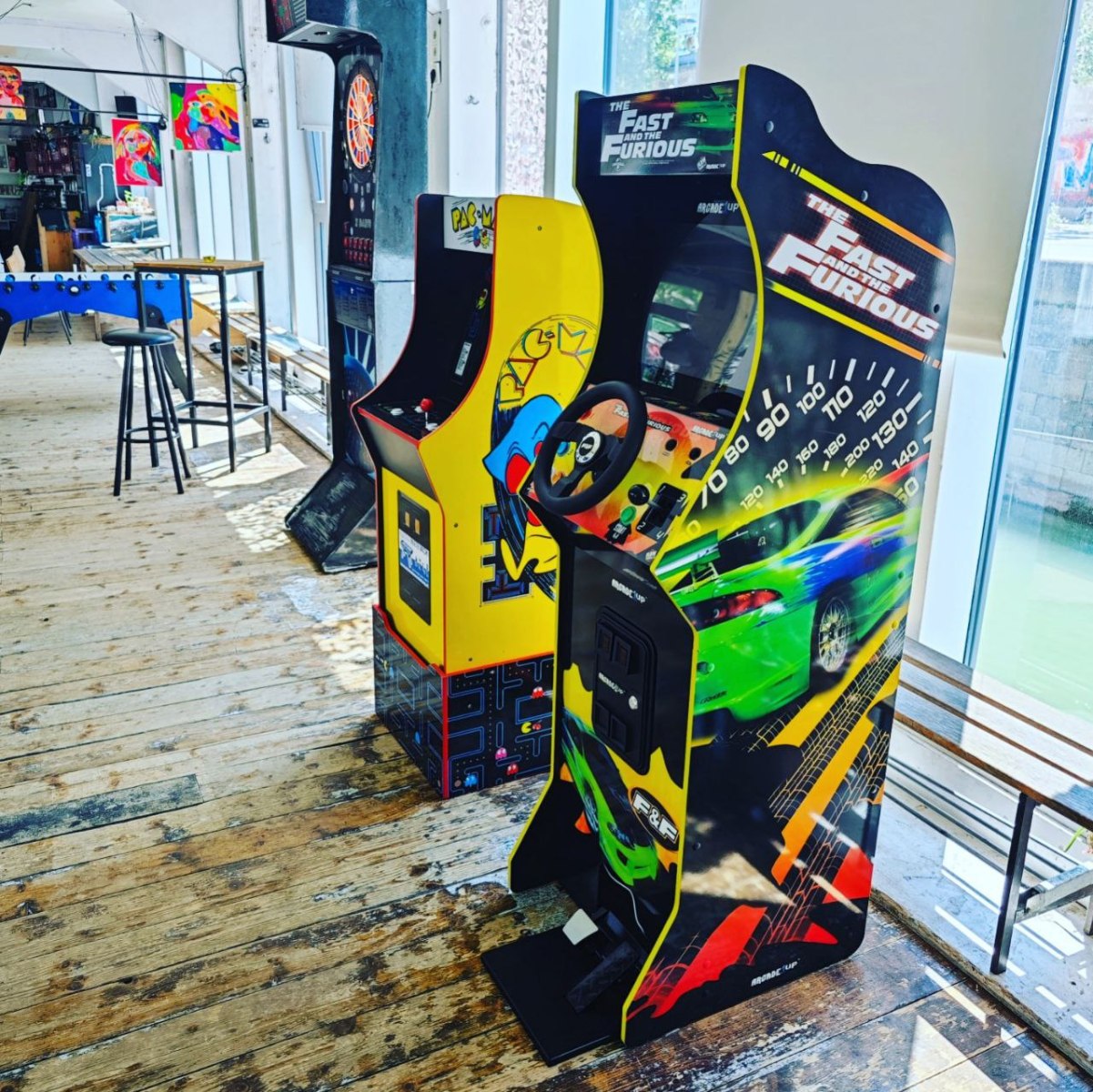 Rennsimulator mit Lenkrad neben einem Pac-Man-Arcade-Automaten
